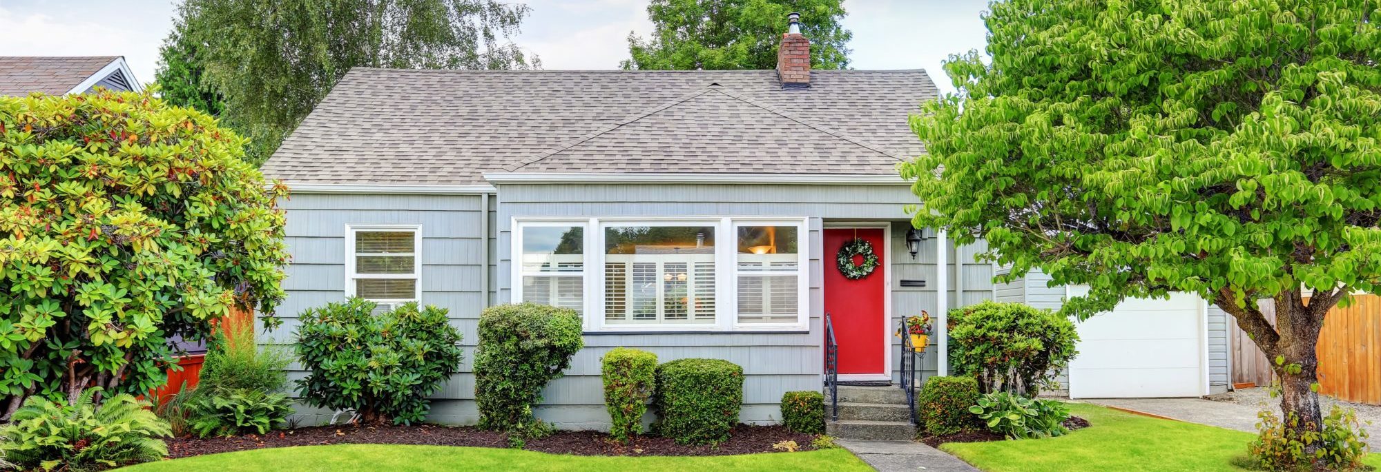 Exterior of small American house with blue paint and red entrance door. Northwest, USA