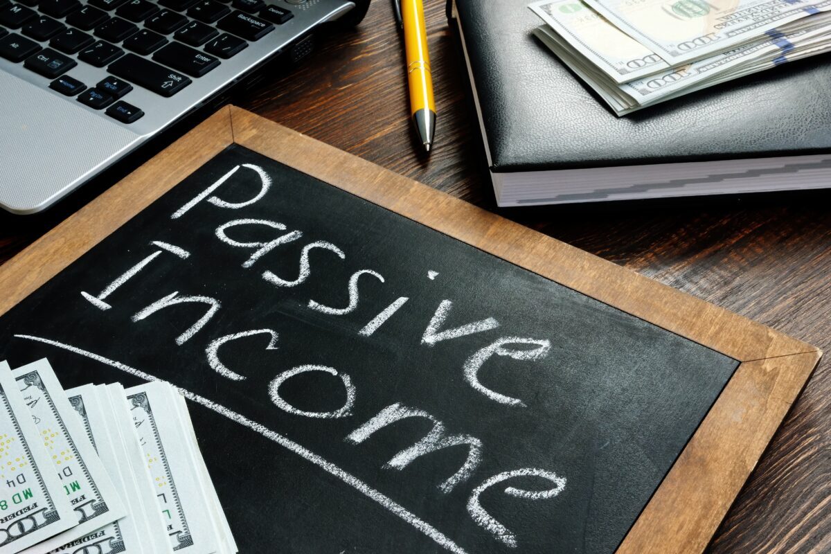 Passive Income Guide for Real Estate Investors, Passive income inscription on the board and a bundle of bills.